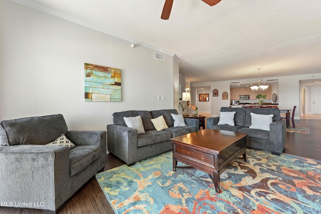 living area featuring ceiling fan with notable chandelier, wood finished floors, visible vents, and ornamental molding