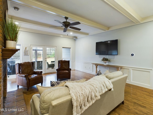 living room with ceiling fan, a brick fireplace, beam ceiling, dark wood-type flooring, and french doors