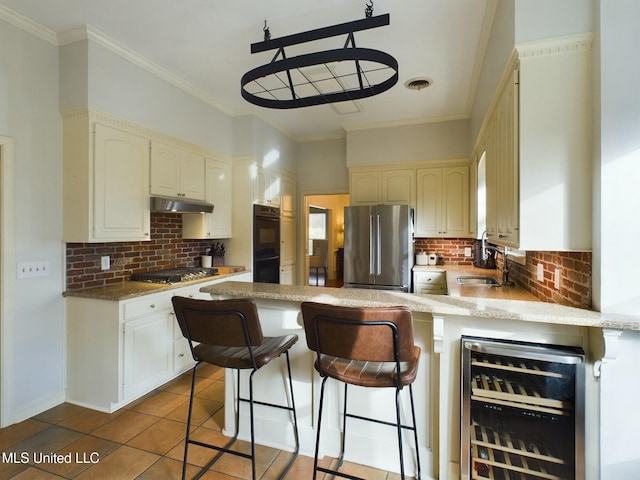 kitchen with wine cooler, decorative backsplash, a kitchen bar, sink, and stainless steel appliances