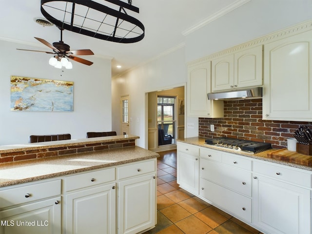 kitchen featuring decorative backsplash, ceiling fan, light tile patterned floors, stainless steel gas stovetop, and crown molding