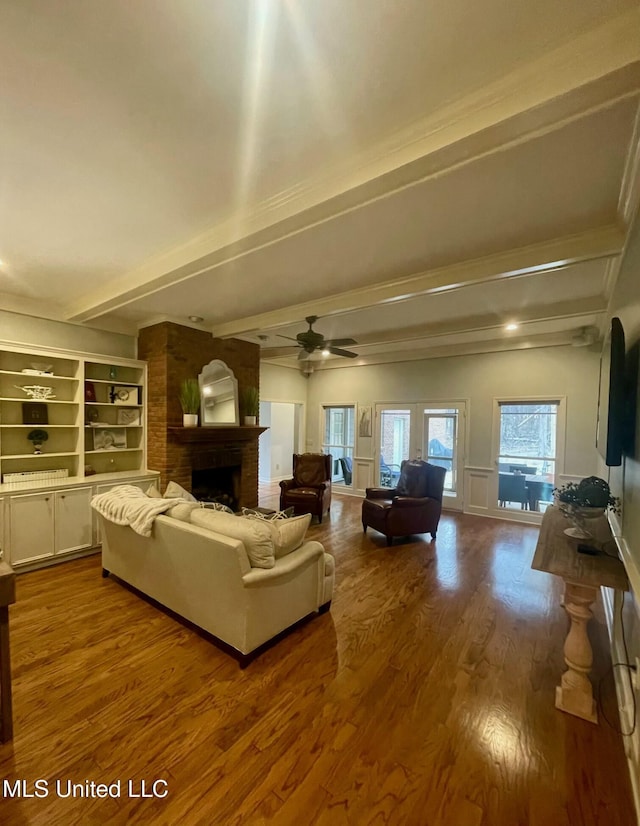 living room featuring ceiling fan, a fireplace, hardwood / wood-style floors, beamed ceiling, and built in features