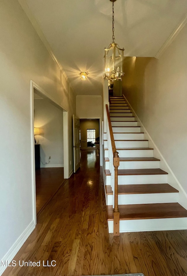 stairway with hardwood / wood-style floors, ornamental molding, and a notable chandelier