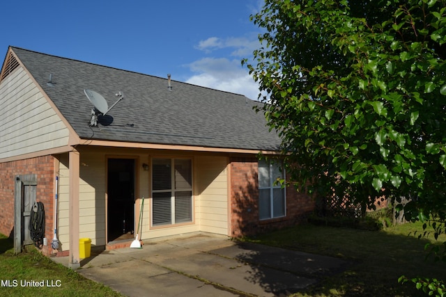 back of property featuring brick siding, a patio area, and a shingled roof