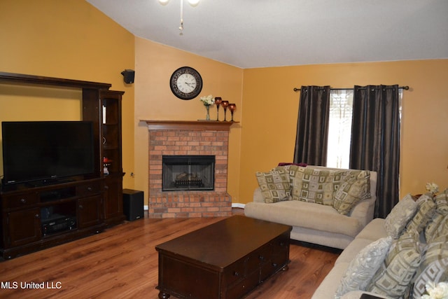living area with lofted ceiling, wood finished floors, and a brick fireplace