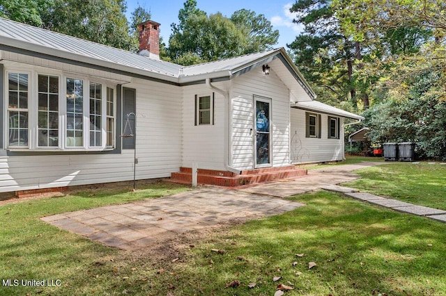 back of house with a patio area and a lawn