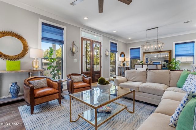 living room with an inviting chandelier, crown molding, and light hardwood / wood-style flooring