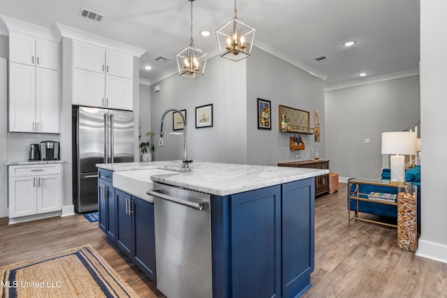 kitchen with blue cabinetry, white cabinetry, an island with sink, and appliances with stainless steel finishes