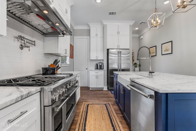 kitchen featuring blue cabinetry, high quality appliances, white cabinetry, and wall chimney range hood