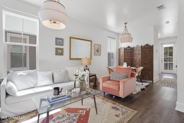 living area with dark wood-style floors, visible vents, and baseboards