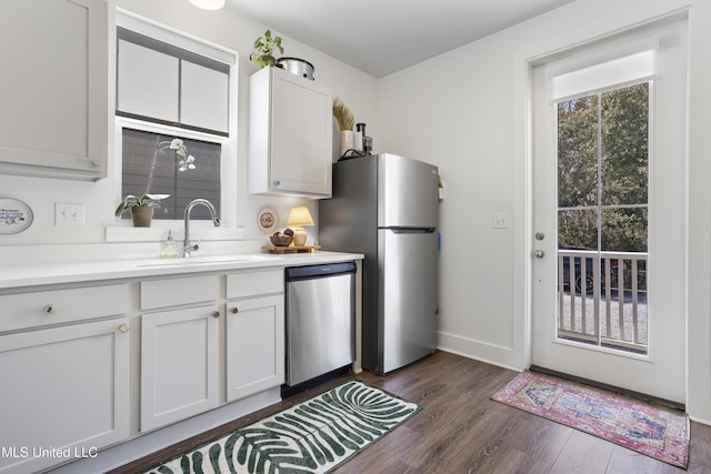 kitchen with appliances with stainless steel finishes, dark wood-style flooring, white cabinets, and a sink