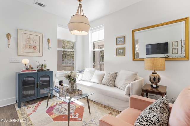 living area with visible vents, baseboards, and wood finished floors