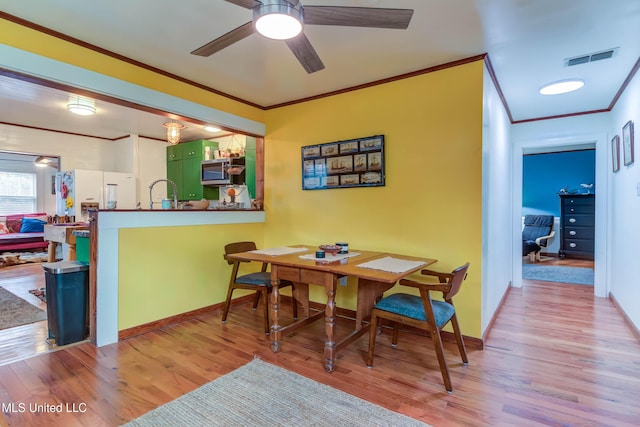 dining room with crown molding, ceiling fan, and light wood-type flooring