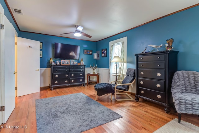 living area with hardwood / wood-style flooring, ceiling fan, and crown molding