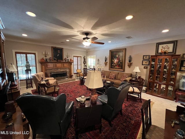 living room featuring ornamental molding, carpet flooring, a fireplace, and ceiling fan