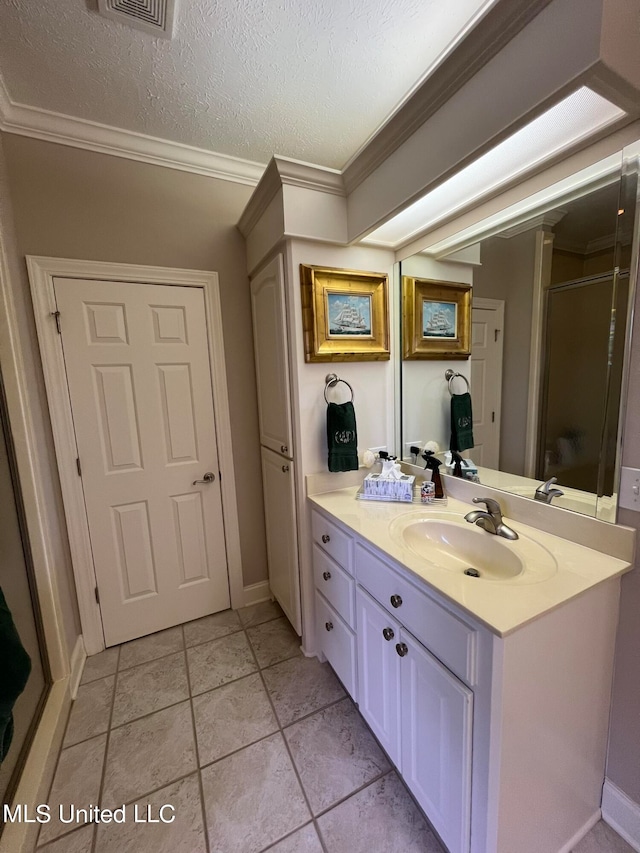 bathroom featuring a shower with door, a textured ceiling, ornamental molding, vanity, and tile patterned floors