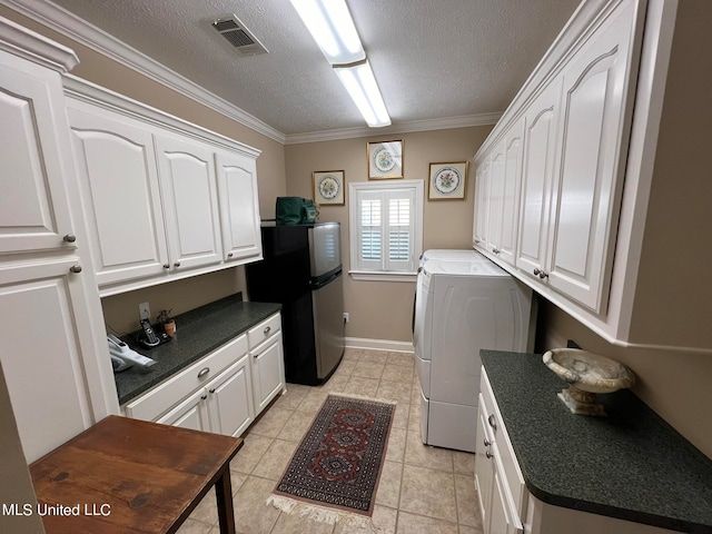 laundry room with crown molding, light tile patterned floors, a textured ceiling, washing machine and dryer, and cabinets