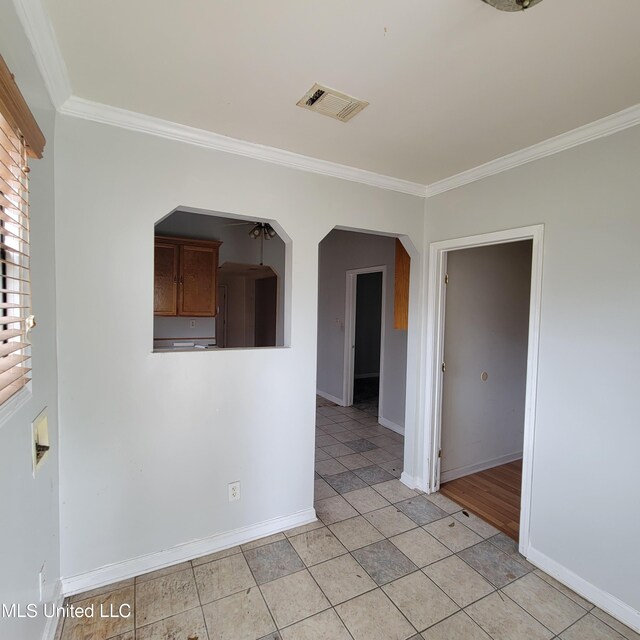 unfurnished room with baseboards, visible vents, crown molding, and arched walkways