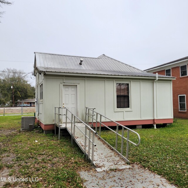 back of house with cooling unit and metal roof
