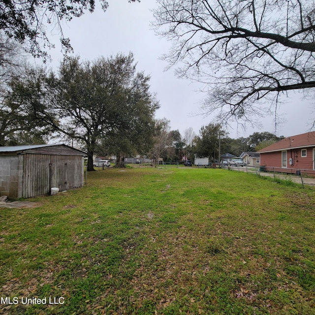 view of yard with an outdoor structure, fence, and a storage unit