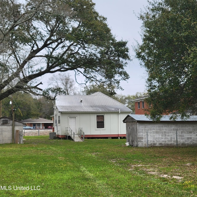 rear view of property with a yard, fence, metal roof, central air condition unit, and entry steps
