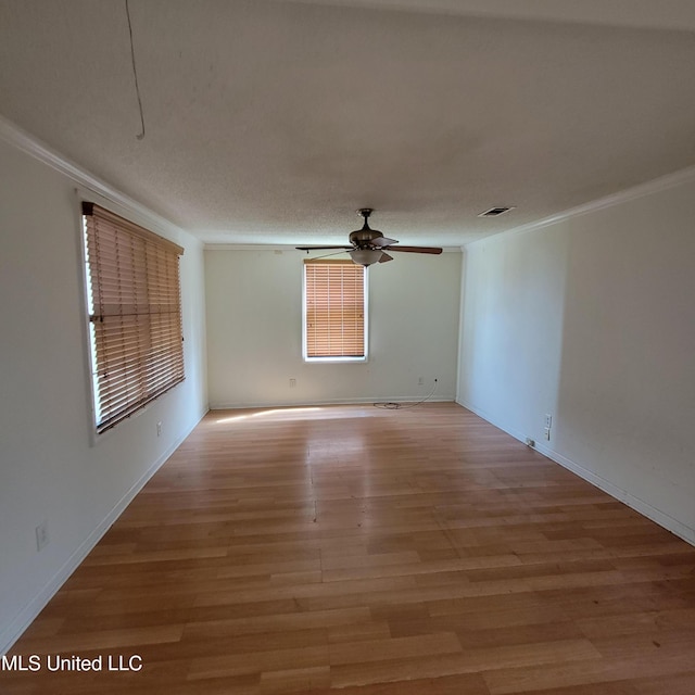 unfurnished room with ceiling fan, crown molding, light wood-type flooring, and visible vents