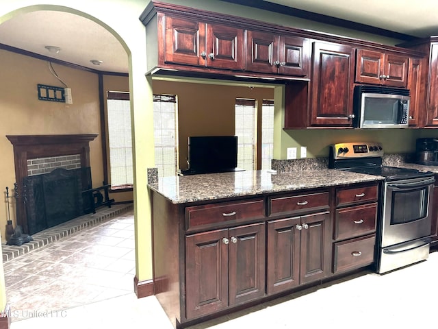 kitchen featuring appliances with stainless steel finishes, ornamental molding, light stone counters, and a brick fireplace