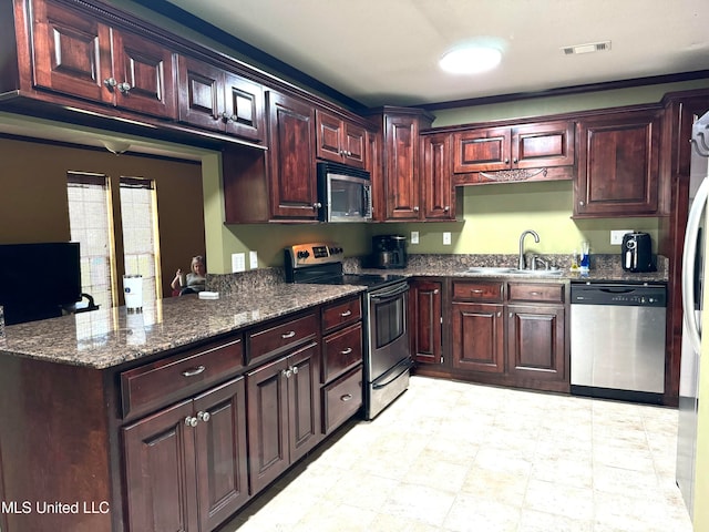 kitchen with sink, stainless steel appliances, dark stone counters, and kitchen peninsula