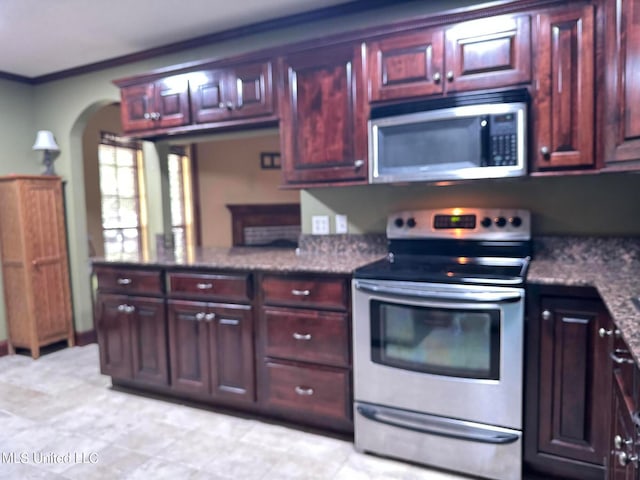 kitchen featuring stainless steel appliances, ornamental molding, and dark stone counters