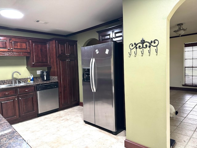 kitchen with ornamental molding, sink, appliances with stainless steel finishes, and dark stone counters