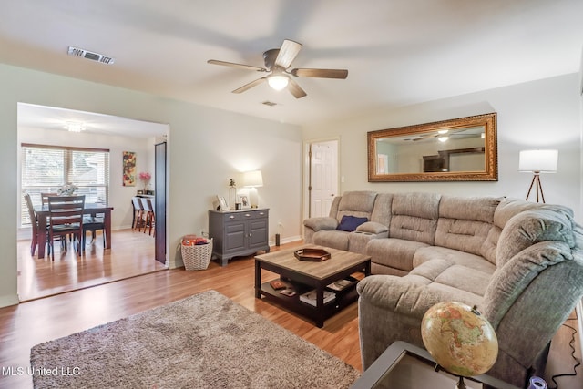 living area featuring visible vents, a ceiling fan, light wood finished floors, and baseboards
