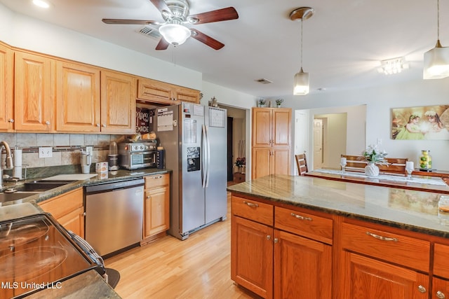 kitchen with a ceiling fan, decorative light fixtures, appliances with stainless steel finishes, a sink, and light wood-style floors
