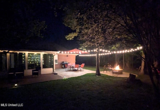 yard at twilight with an outdoor fire pit and a patio area