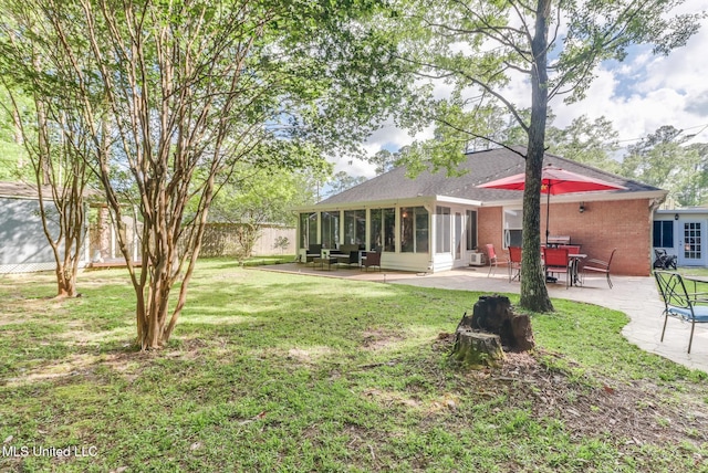 back of property with brick siding, a sunroom, a fenced backyard, a patio area, and a lawn
