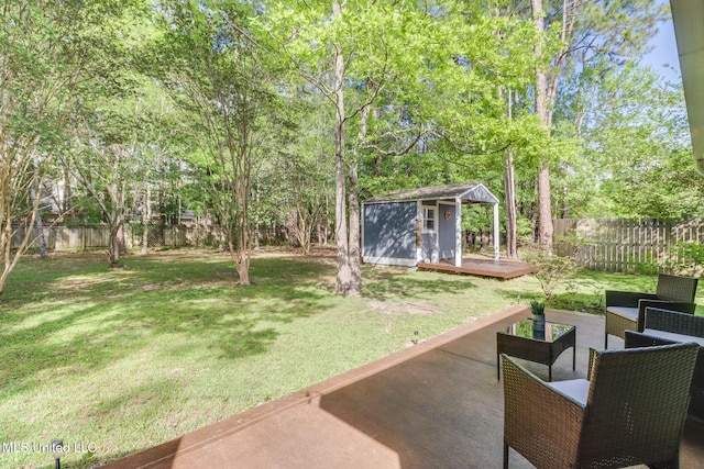 view of yard with a deck, a shed, a fenced backyard, an outbuilding, and a patio