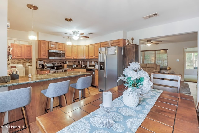 dining room featuring washing machine and clothes dryer, ceiling fan, and visible vents