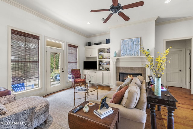 living room with light hardwood / wood-style floors, crown molding, a fireplace, and ceiling fan