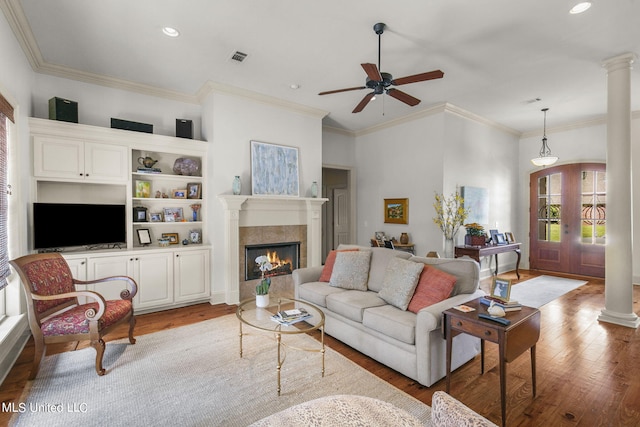 living room with ornamental molding, a tiled fireplace, light wood-type flooring, and ceiling fan