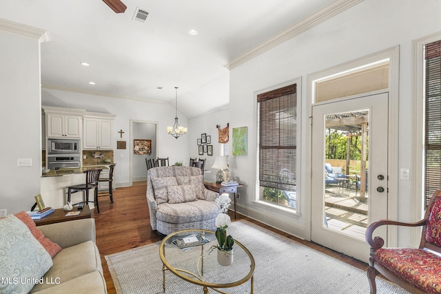 living room with lofted ceiling, ornamental molding, a notable chandelier, and dark hardwood / wood-style floors