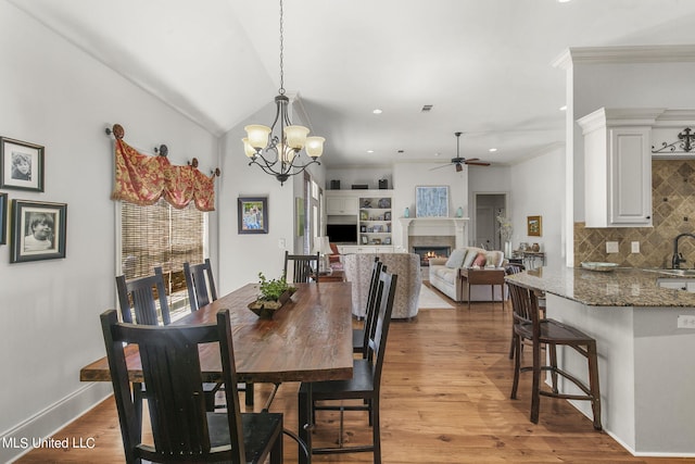 dining space with ornamental molding, hardwood / wood-style flooring, sink, and ceiling fan with notable chandelier