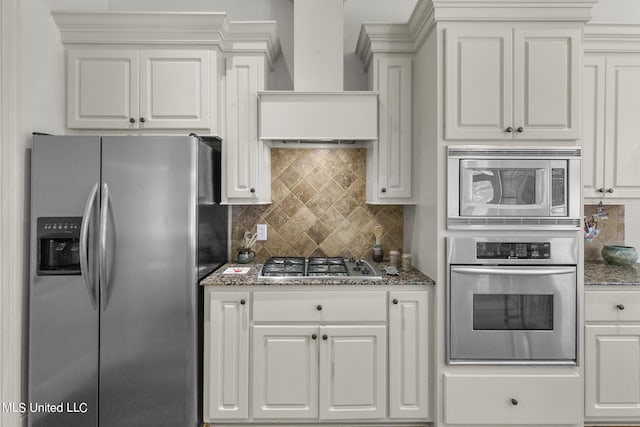 kitchen featuring appliances with stainless steel finishes, backsplash, dark stone counters, custom exhaust hood, and white cabinets