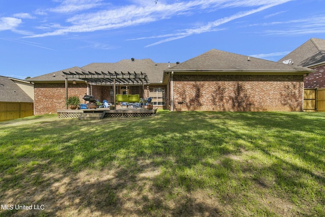 rear view of house with a wooden deck, a lawn, and a pergola