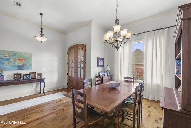 dining room featuring an inviting chandelier, crown molding, light hardwood / wood-style floors, and french doors