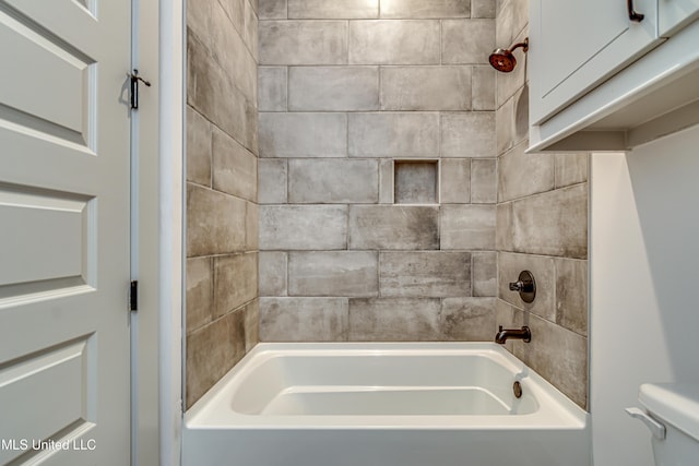 bathroom featuring tiled shower / bath combo and toilet