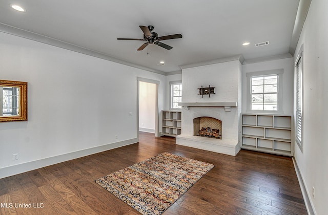 unfurnished living room featuring ceiling fan, a healthy amount of sunlight, dark wood-type flooring, and crown molding