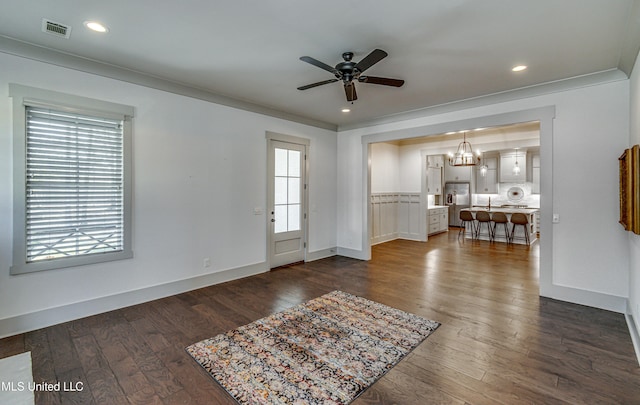 interior space with ceiling fan with notable chandelier, dark hardwood / wood-style flooring, and crown molding