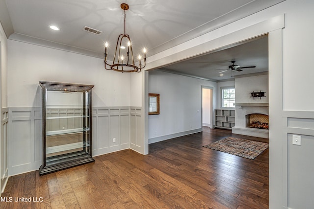 unfurnished dining area featuring ornamental molding, ceiling fan with notable chandelier, and wood-type flooring