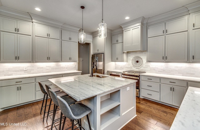 kitchen featuring light stone countertops, appliances with stainless steel finishes, sink, a kitchen island with sink, and custom range hood