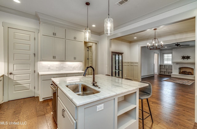 kitchen featuring decorative light fixtures, sink, an island with sink, dark hardwood / wood-style flooring, and ceiling fan with notable chandelier