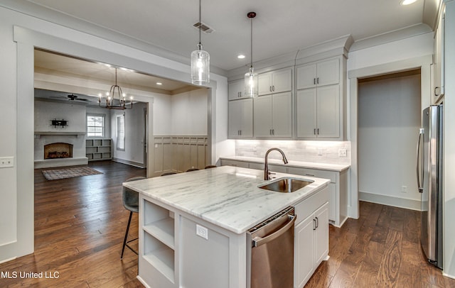 kitchen with ceiling fan with notable chandelier, decorative light fixtures, stainless steel appliances, an island with sink, and sink