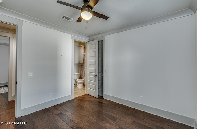 unfurnished bedroom with ceiling fan, dark wood-type flooring, and connected bathroom